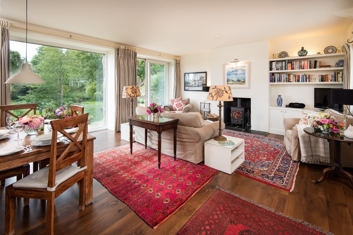 Brunton Burn - the spacious open-plan sitting room with wood burning stove, views of the burn and dining space for four guests