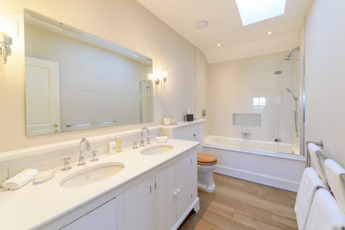 Fenton Lodge - North bedroom en suite bathroom with bath and shower over, double basins and WC