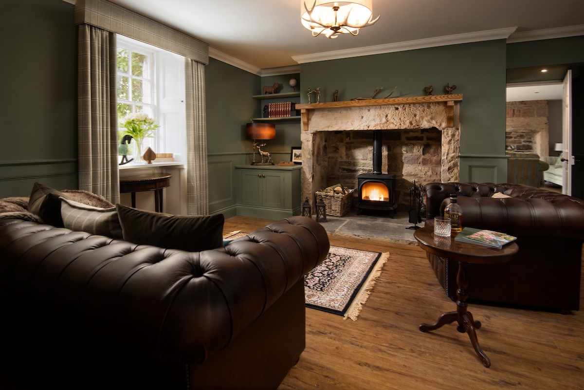 Brockmill Farmhouse - snug with leather Chesterfield style sofa and armchair set around wood-burning stove