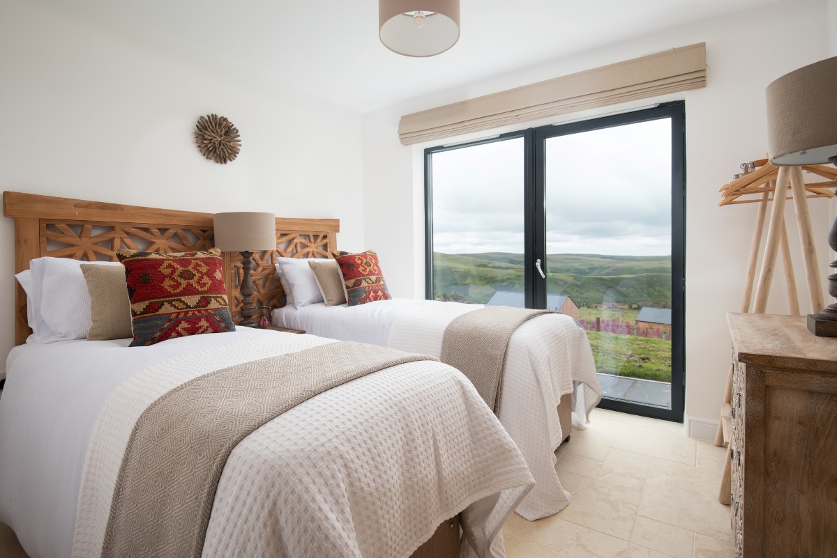 The Maple - bedroom two configured as twin beds with views of the Coquet valley from the patio doors