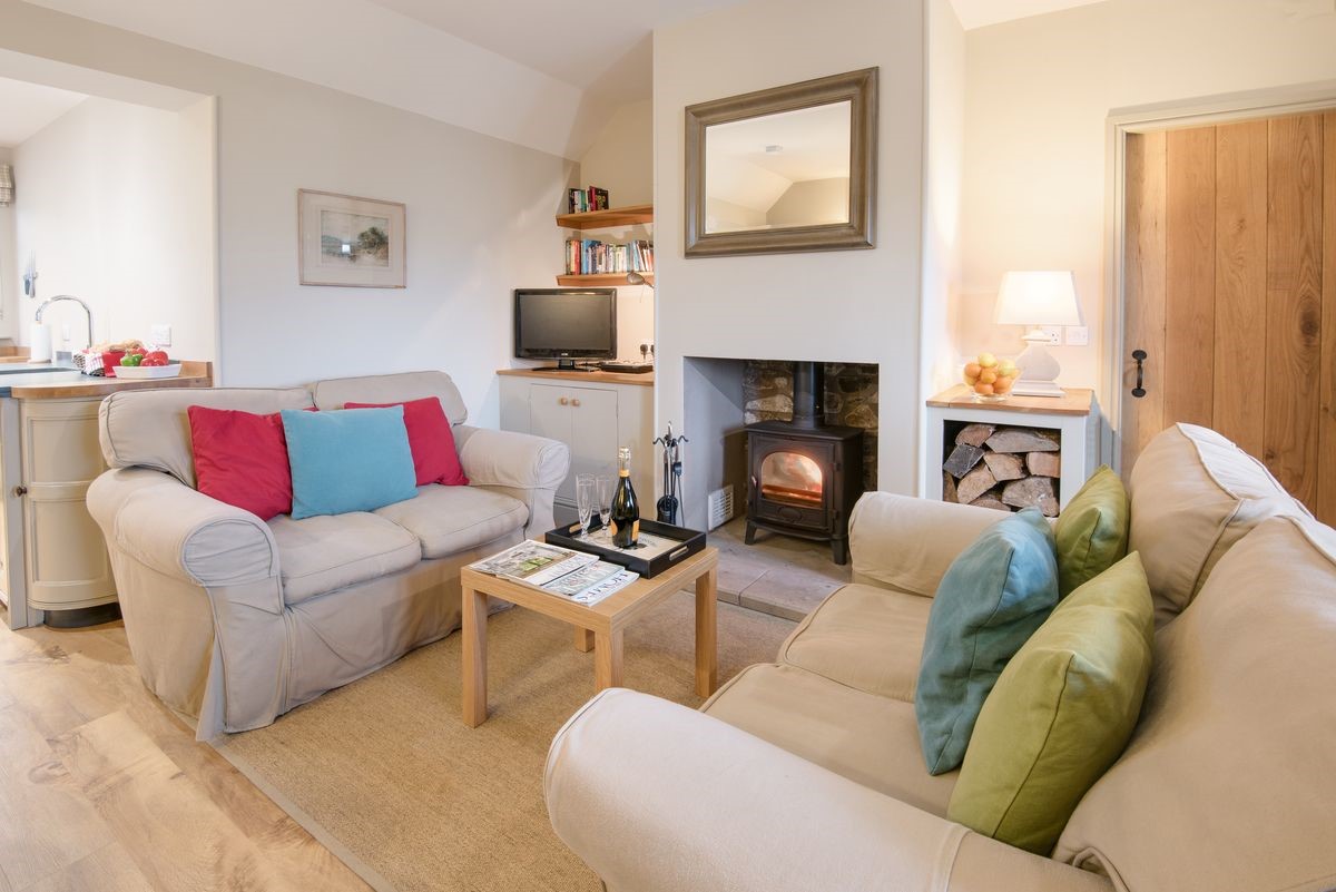 Barley Hill Cottage - the living area with wood burning stove with door leading to bedroom one
