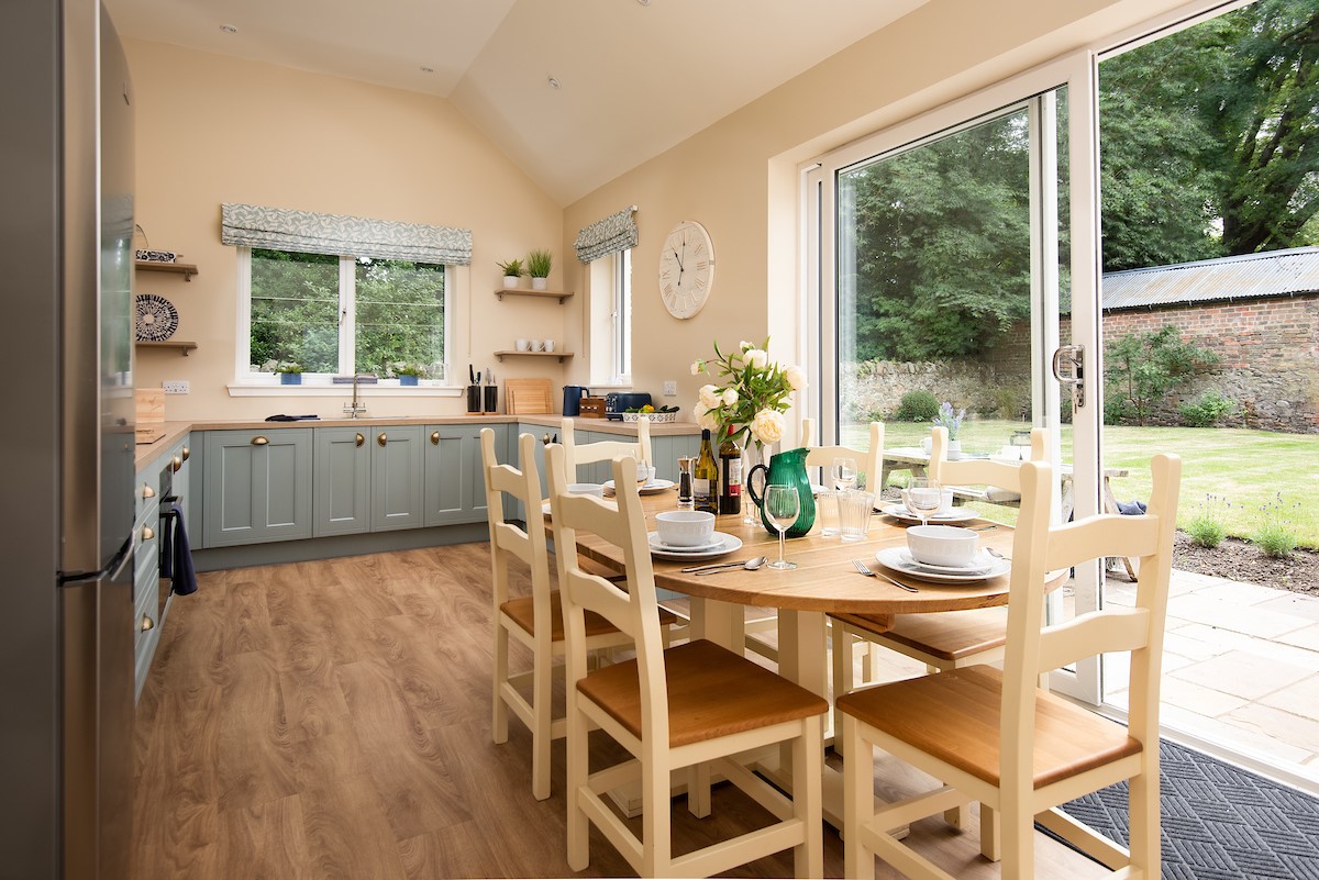 The Coach House, Kingston - kitchen with dining area and doors leading into garden