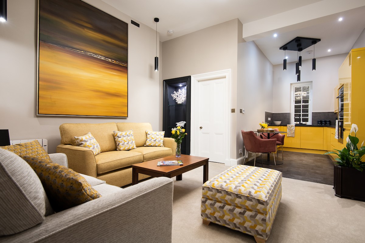 The Scott Apartment - the apartment's open-plan living space has a spacious seating area and sleek yellow kitchen