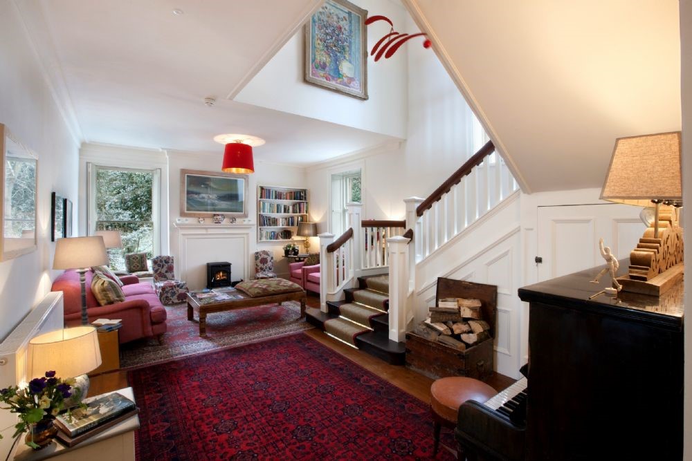 Brunton House - large hall with staircase, seating area, wood-burning stove and piano