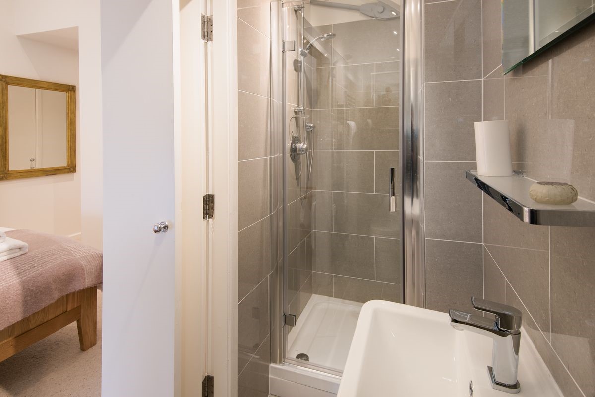 Budle Bay Loft - bedroom one en suite bathroom with walk-in shower, WC and basin