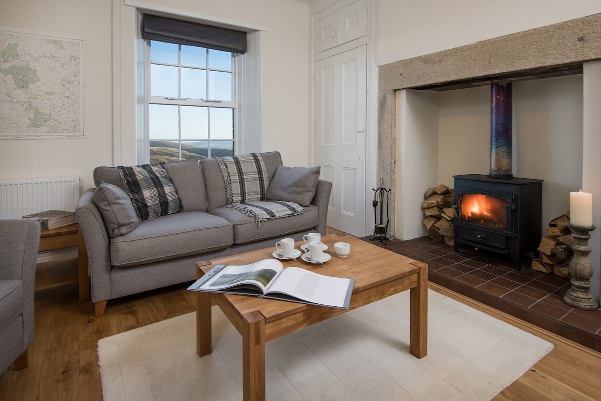 Chaffinch Cottage - sitting room with sofa, coffee table and wood burning stove