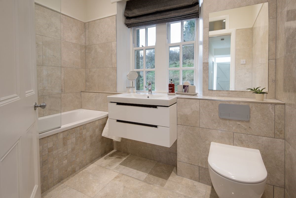 Chaffinch Cottage - tiled family bathroom with bath and shower over, WC and basin