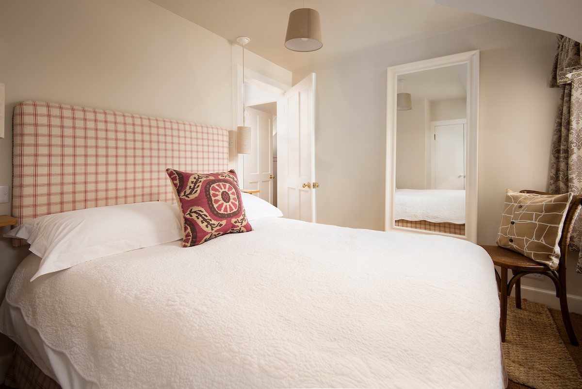 Swan's Nest - bedroom two with double bed with crisp white linen and gingham over-sized headboard