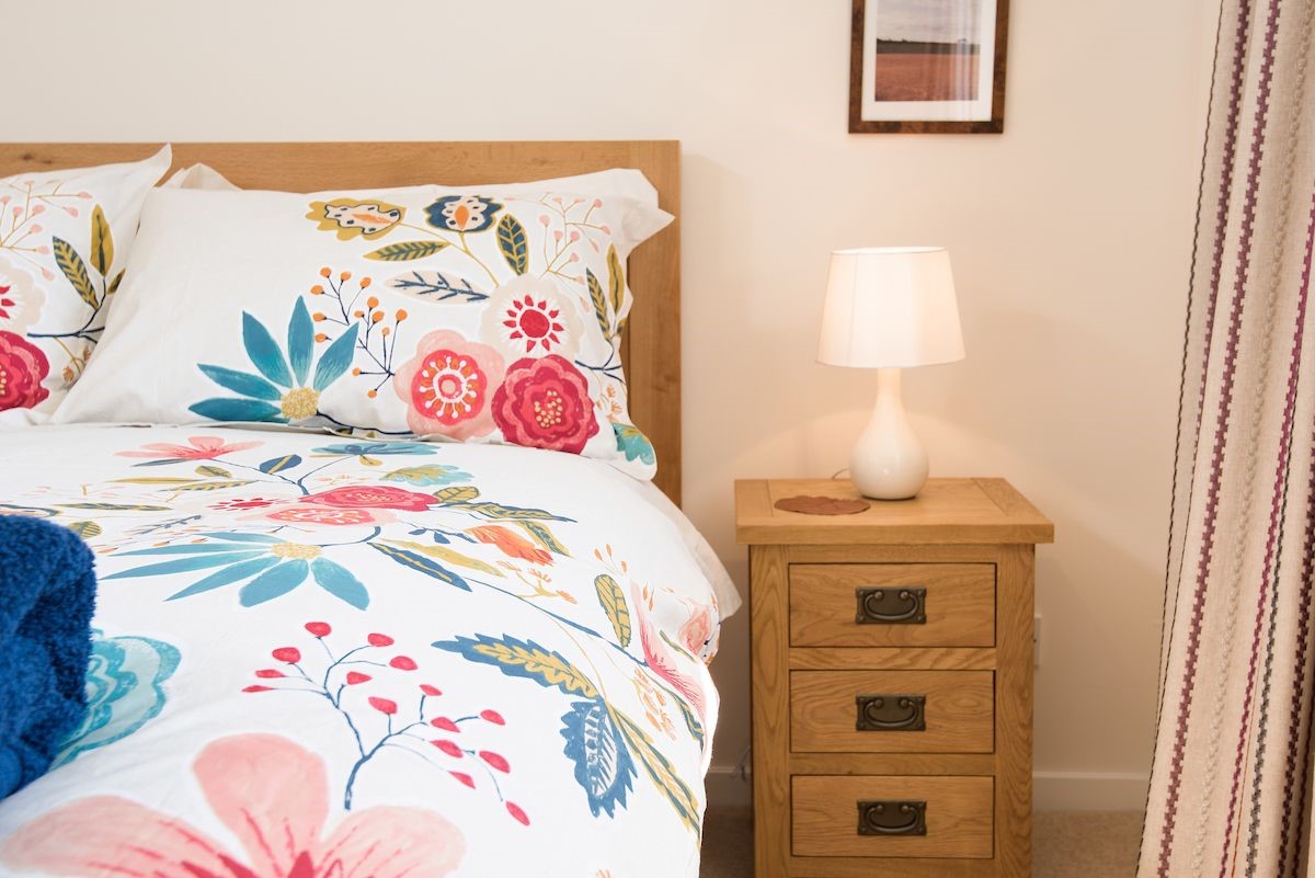 Coldstream Coach House - bedroom two with floral bedding and side table