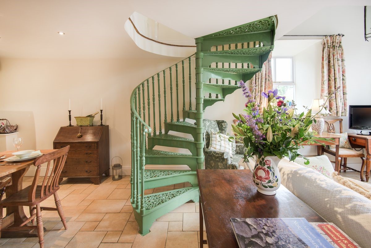 East Cottage - statement green spiral staircase from the open-plan living area up to the first floor