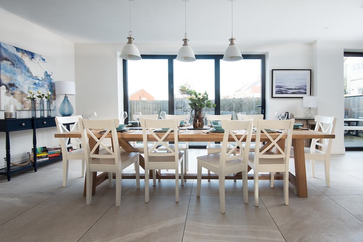 Duneside House - large dining table in front of the bi-fold doors seating up to 10 guests