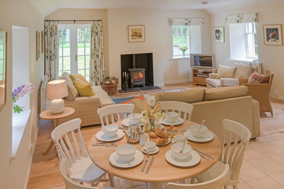 Gardener's Cottage - open-plan living area with dining table and wood burning stove