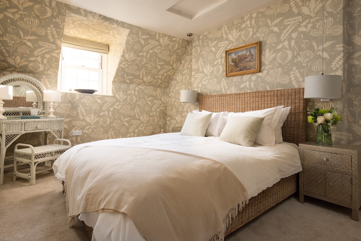 Bughtrig Cottage - bedroom one features a king size bed draped in crisp white linen