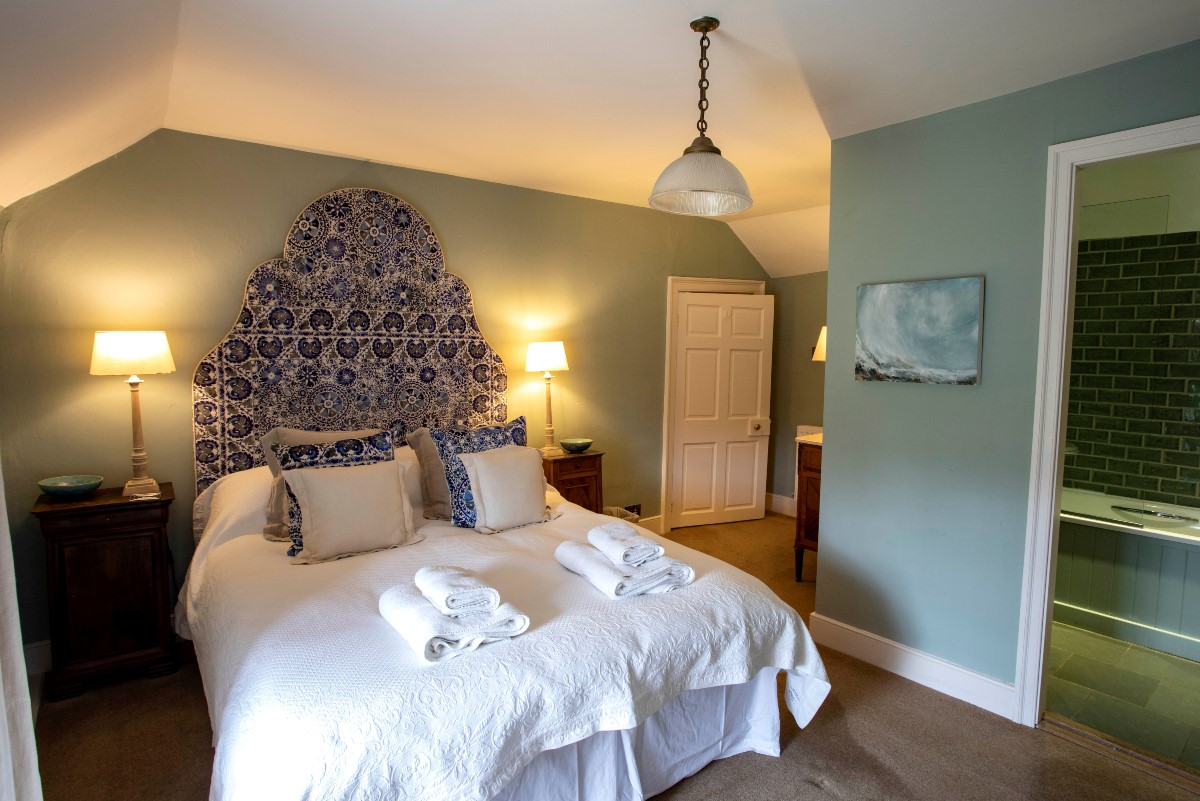 The Boathouse - bedroom four with large patterned headboard and en suite bathroom