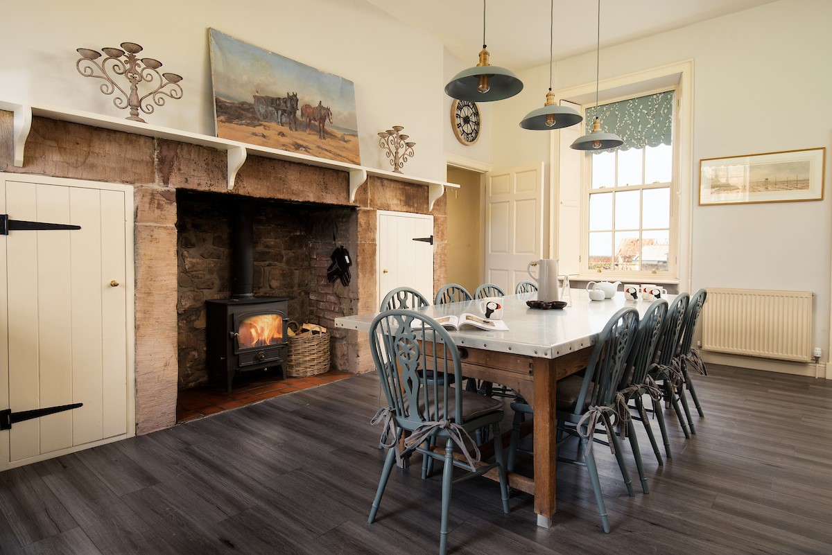 East House - spacious kitchen with dining table and seating for informal dining set in front of the inglenook fireplace with wood burner