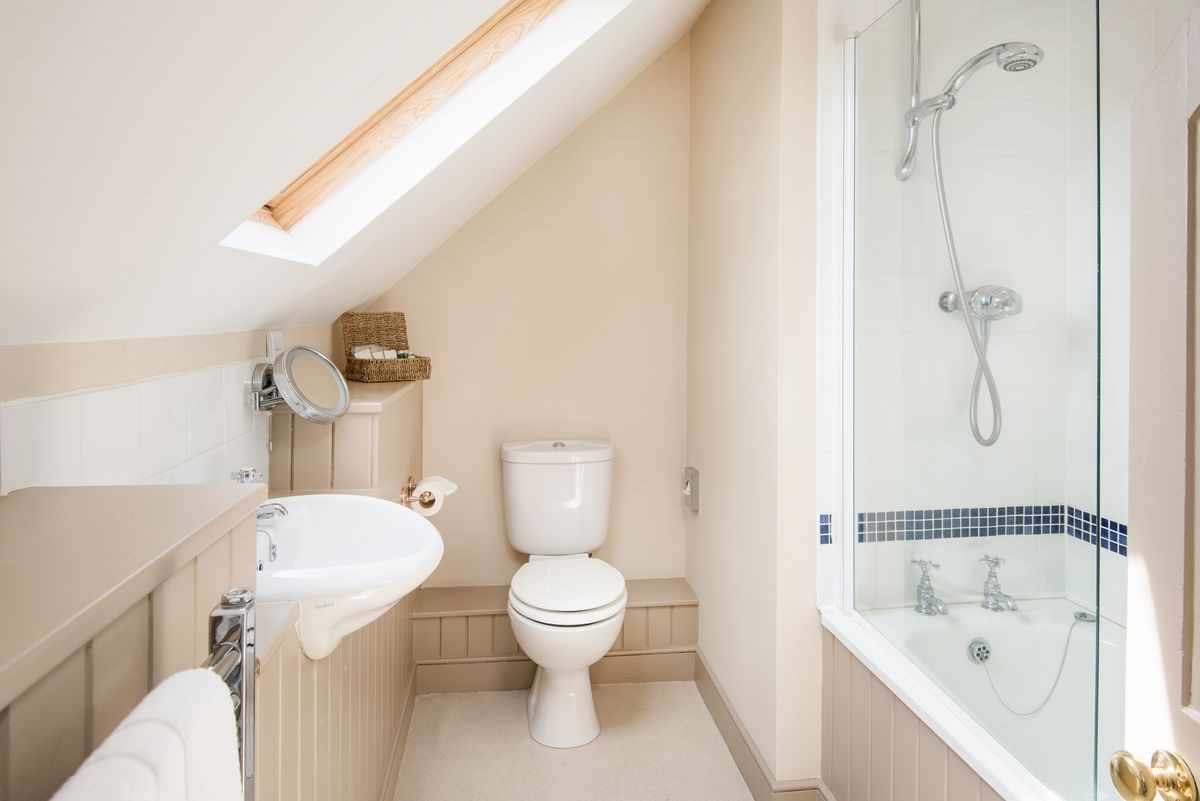 College Cottage - bedroom two en suite bathroom with basin, WC and bath with shower over