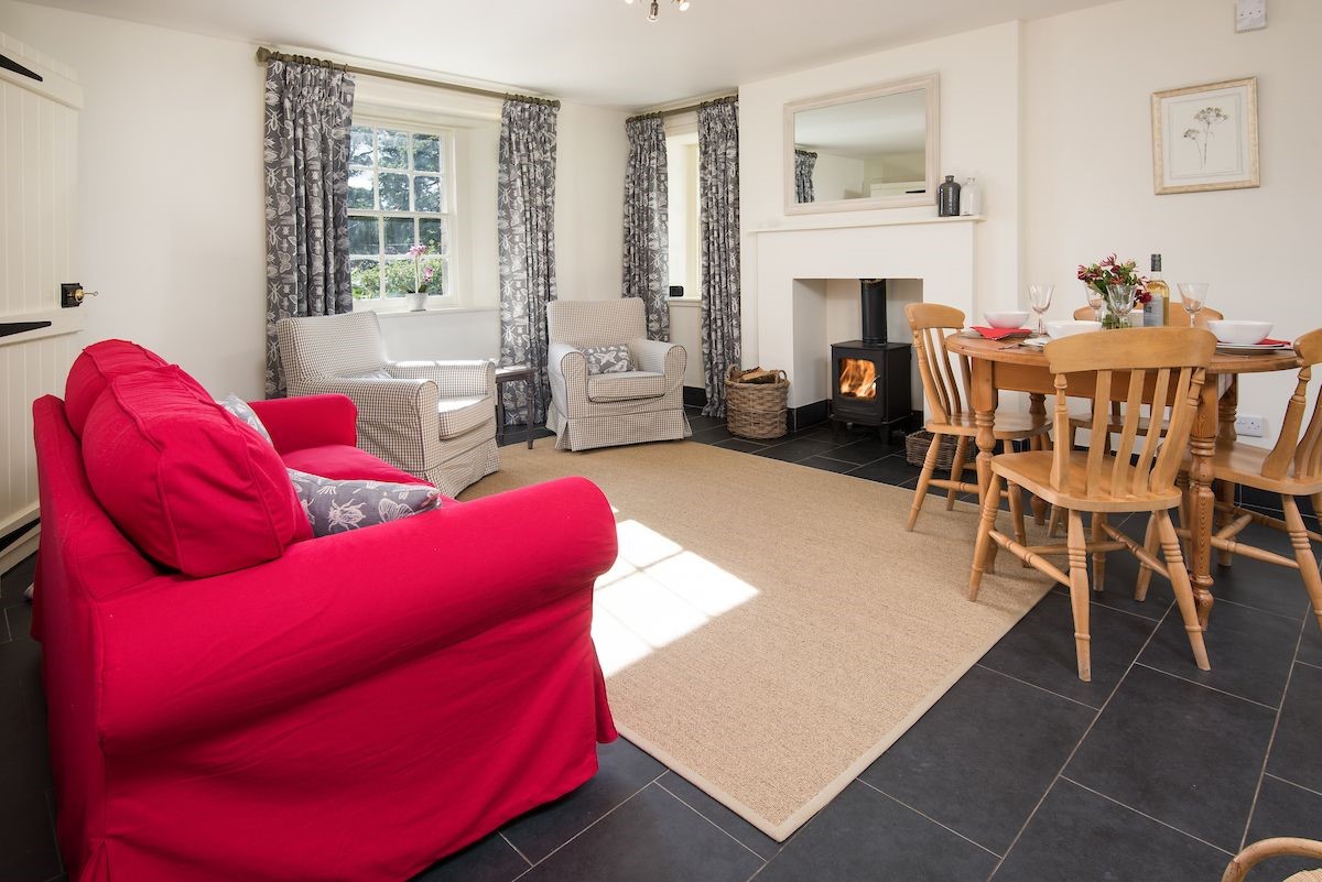 Garden Cottage - open-plan living area with dual aspect views, wood burning stove and dining space for four guests