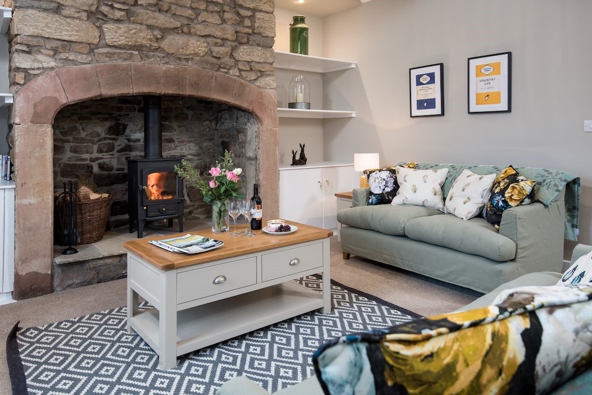Curlew Cottage - sitting room with large inglenook fireplace, wood burning stove, sofas and coffee table
