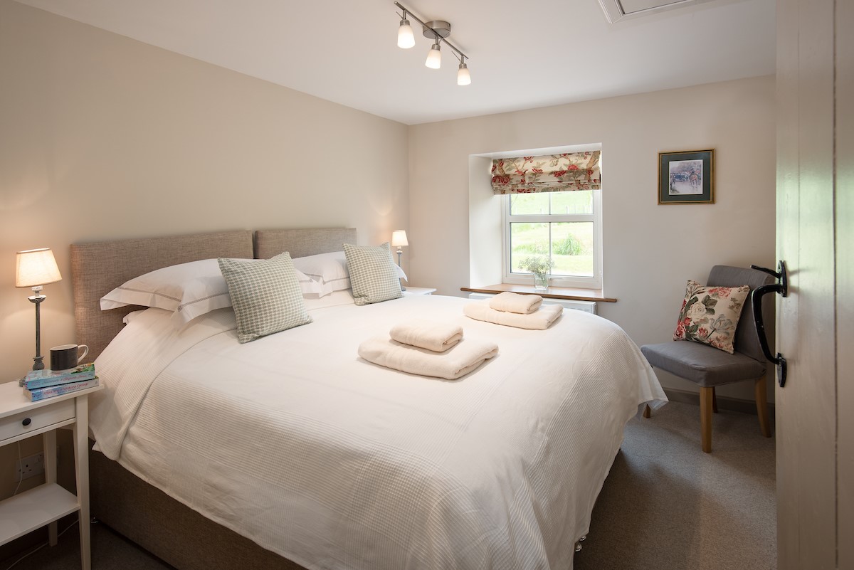 Dipper Cottage - bedroom two with zip and link beds, side tables and en suite bathroom