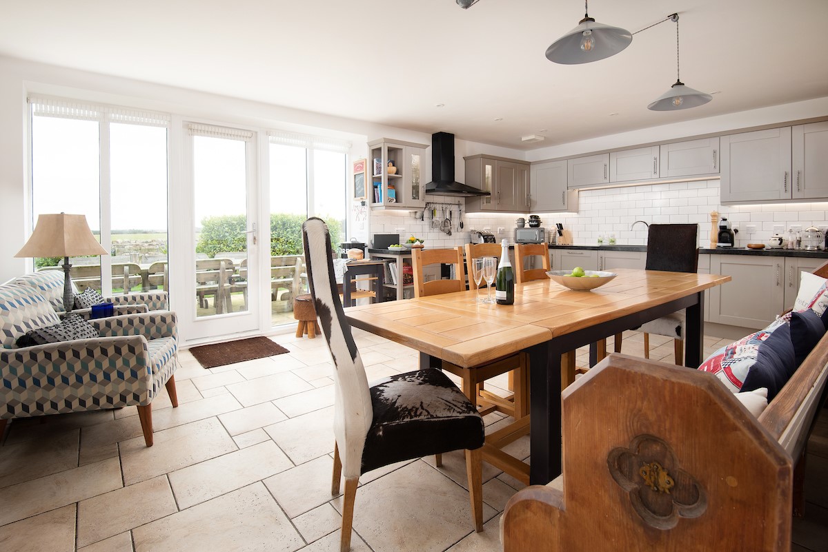 Moo House - large dining table situated in front of the large windows and patio doors with views of the garden