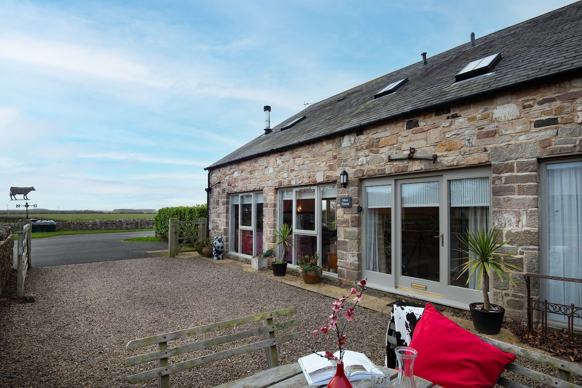 Moo House - front aspect of the property with gravelled parking area and outdoor dining furniture