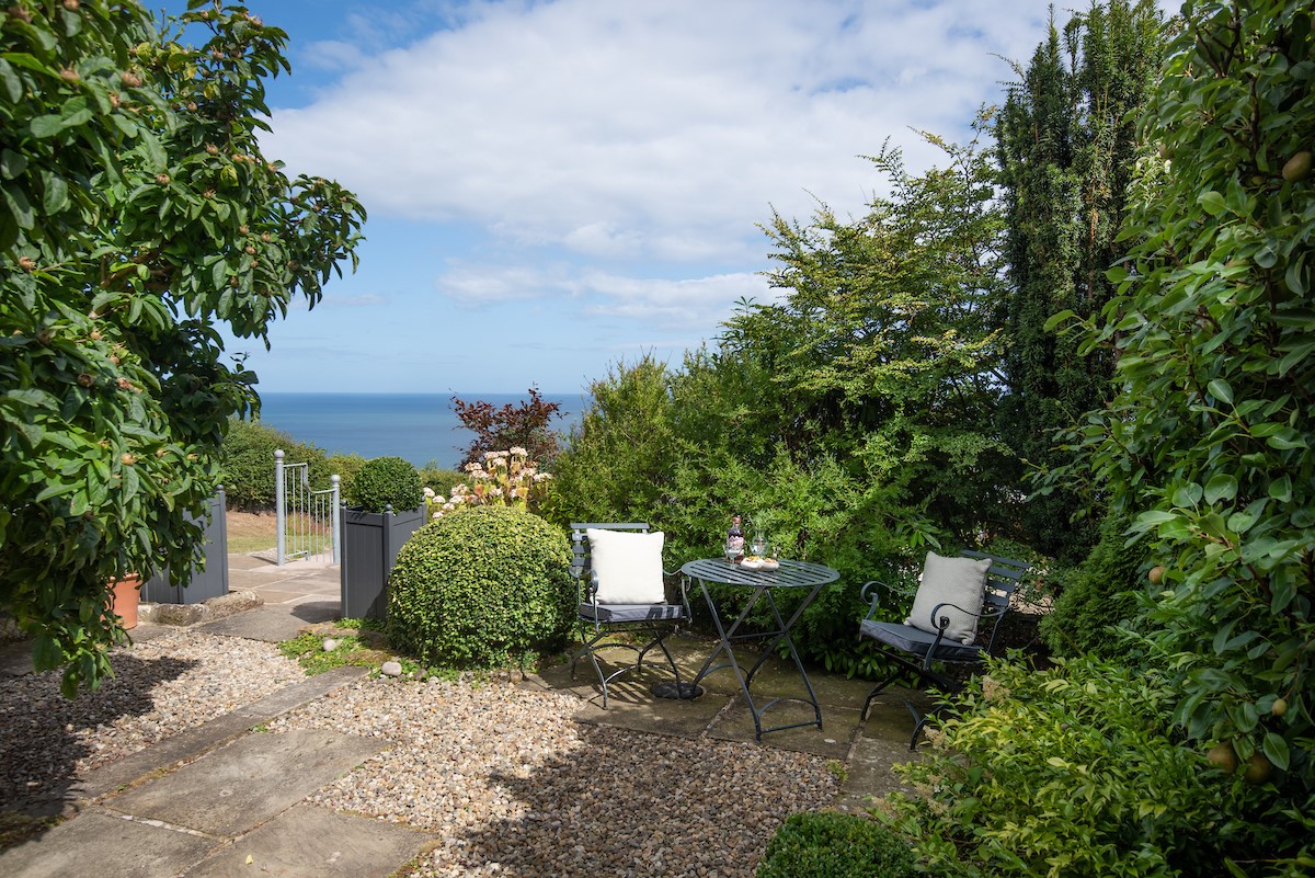 Bay View Cottage - the secluded patio area, with built in BBQ,  resplendent with established greenery and an espalier pear tree