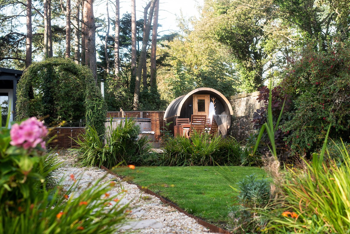 East Lodge Home Farm - pretty garden surrounded by trees with cabin and sauna pod