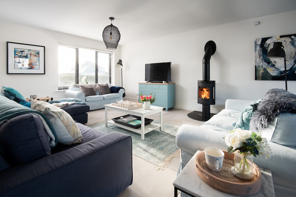 Duneside House - sitting room with modern log burner, comfortable sofas and Smart TV with Blu-ray player