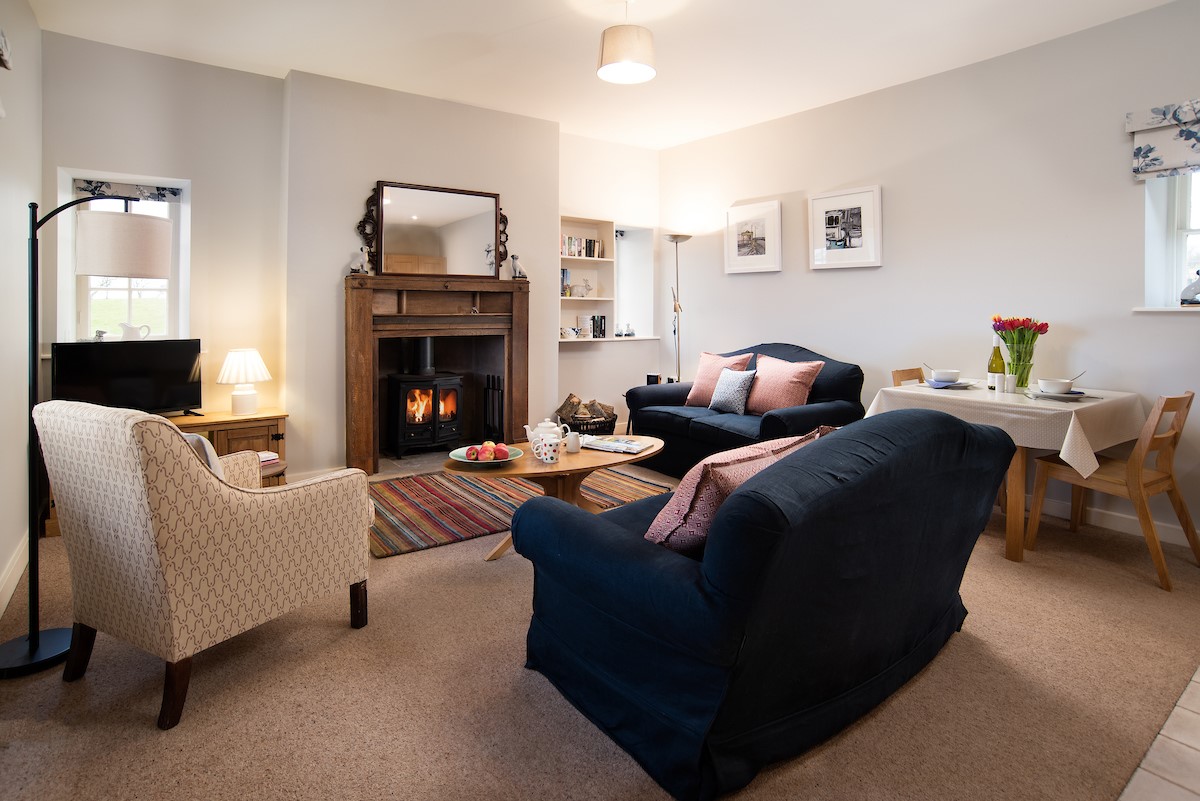 The Bothy at Cheswick - sitting room with comfortable seating, wood burner and dining area in the open-plan living space