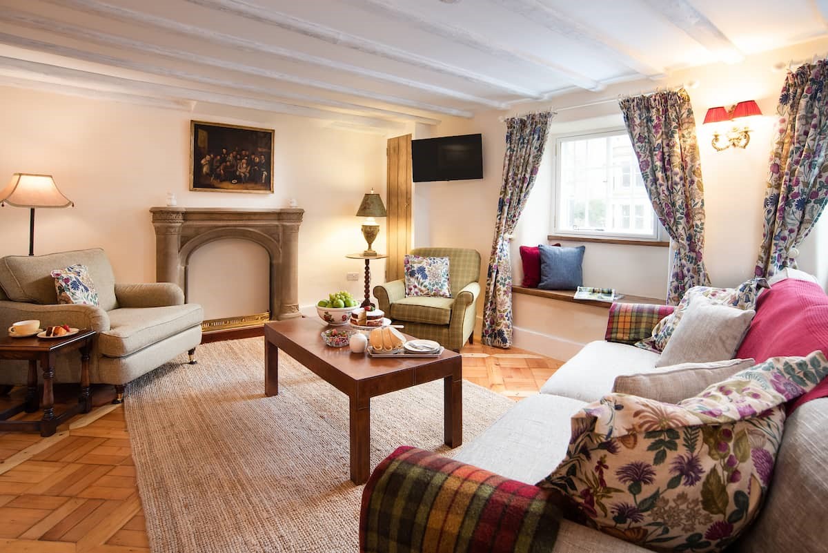 The Craftsman's Cottage - spacious sitting room with ample seating for guests and a decorative stone mantelpiece