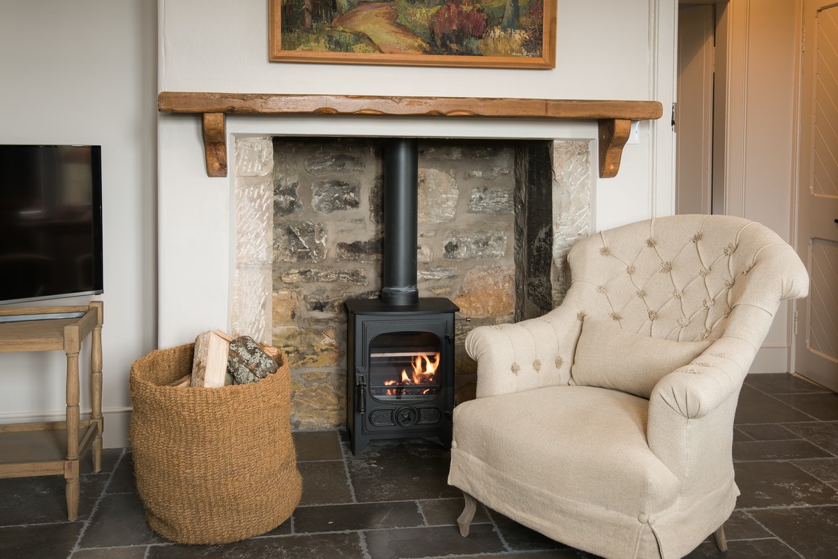Park End - wood burner in sitting room with basket of logs provided and comfortable armchair