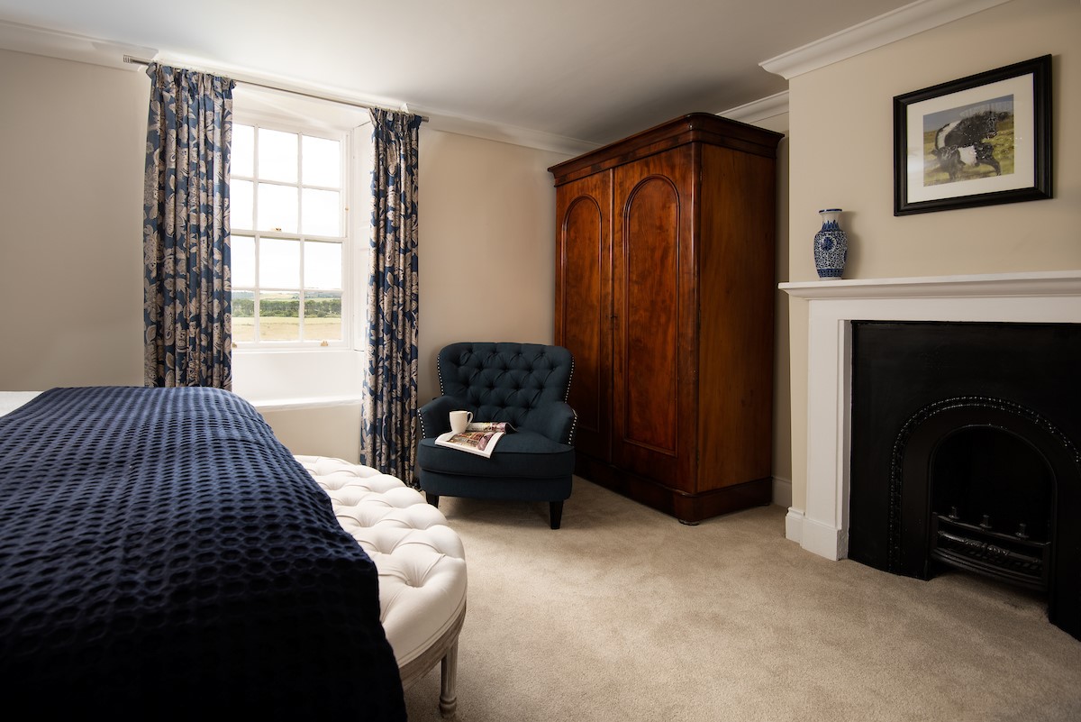 Brockmill Farmhouse - bedroom two with decorative feature fireplace and large south-facing sash window with original shutters overlooking the garden