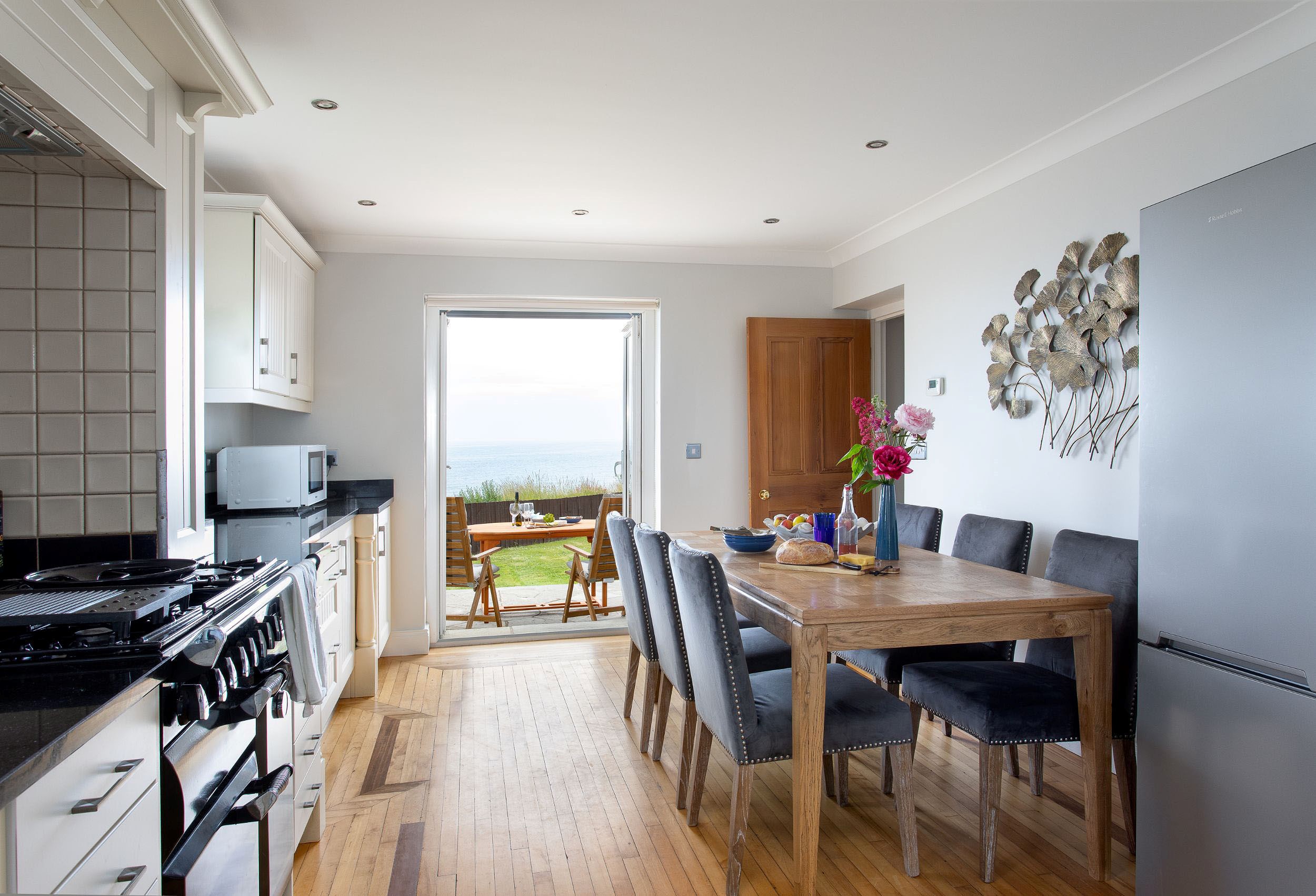Sea Breeze - kitchen and dining table with French doors beyond opening out onto the garden