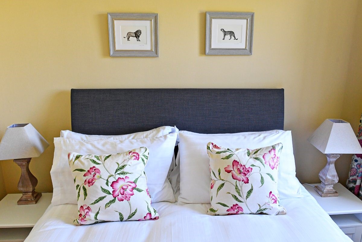 Fordel Cottage - bedroom one with kind size bed dressed in crisp white linen with delicate floral cushions