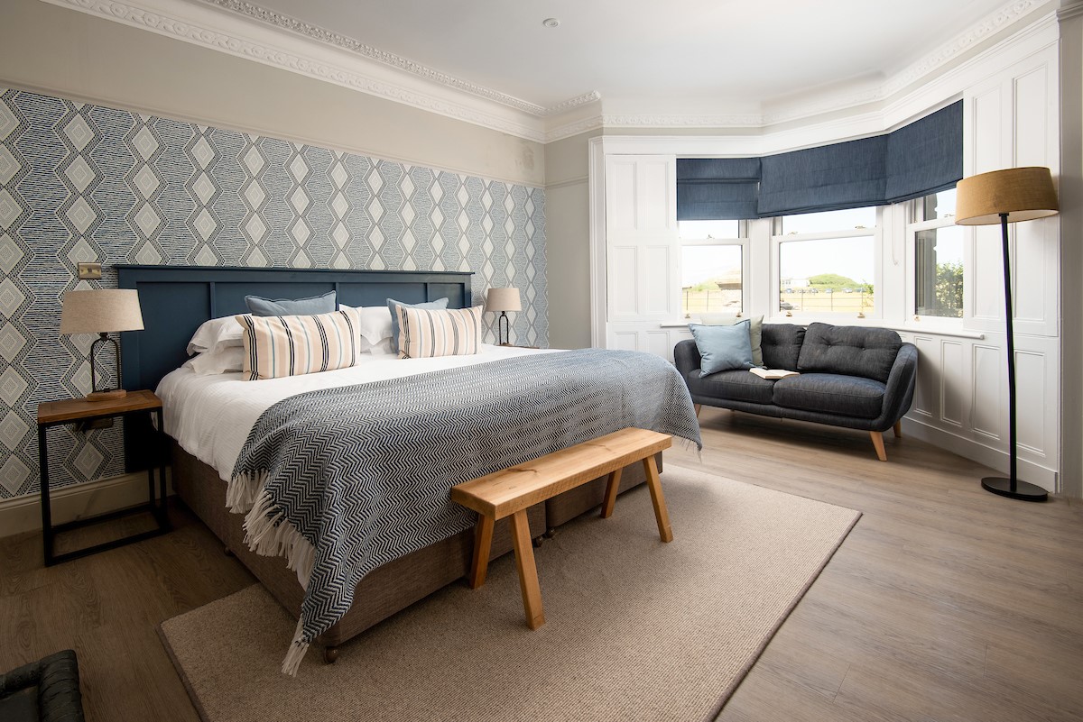 Castle View, Bamburgh - bedroom one located on the ground floor with a large bay window with sofa
