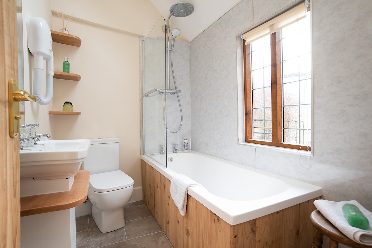 The Craftsman's Cottage - family bathroom featuring a bath with shower over