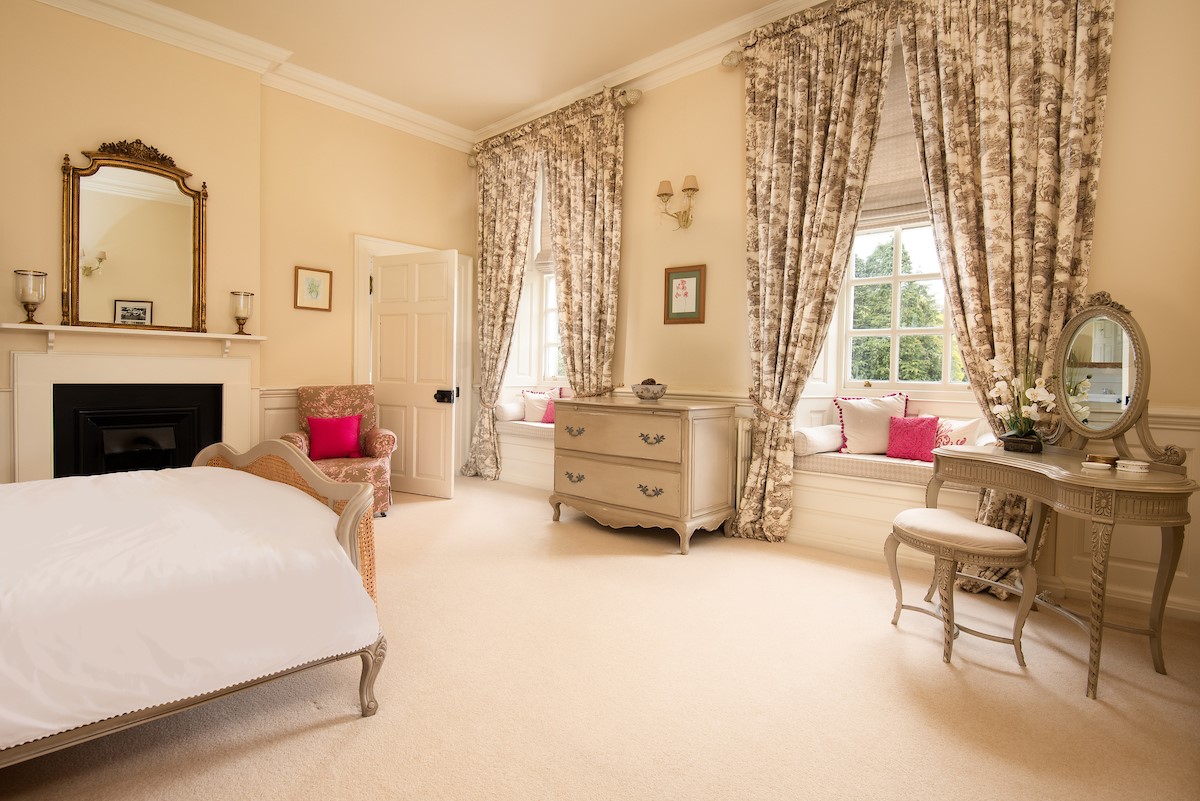 Eslington East Wing - bedroom three with king size bed, dressing table with mirror and stool, and decorative fireplace