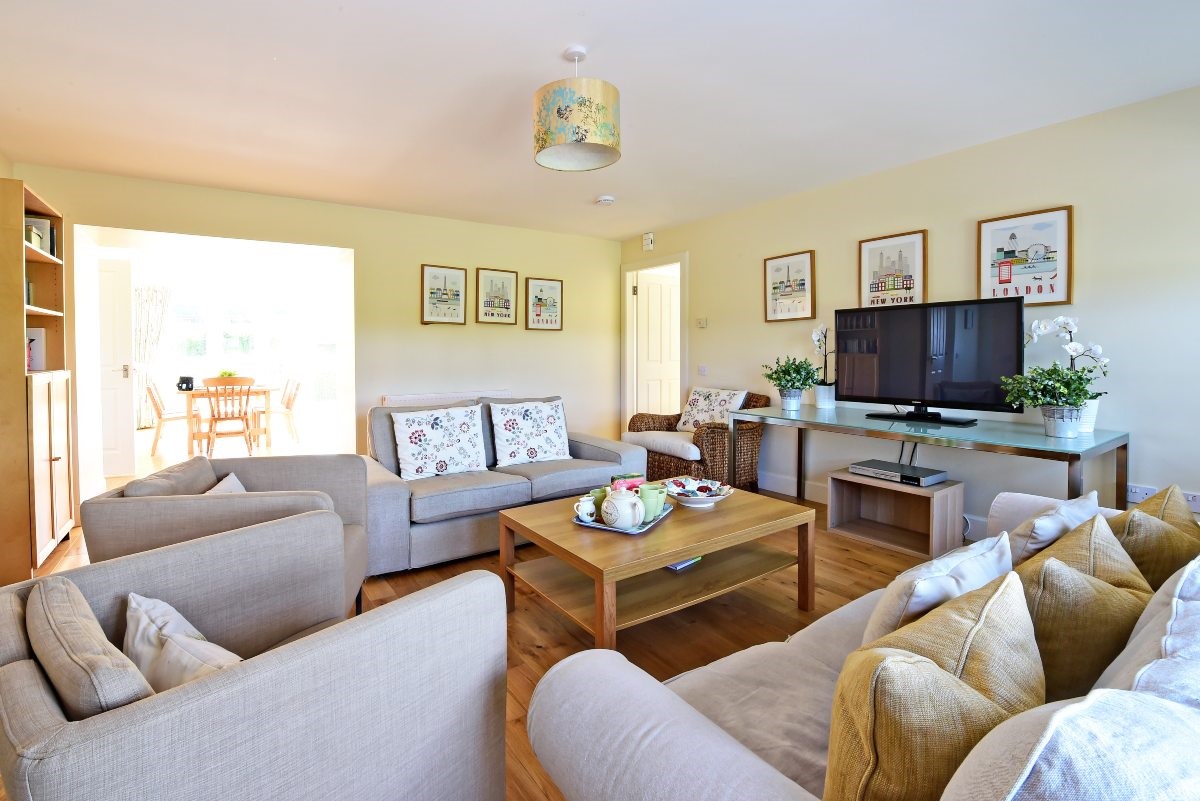 Hawthorn House - sitting room with two sofas and three single armchairs with TV and coffee table for playing games