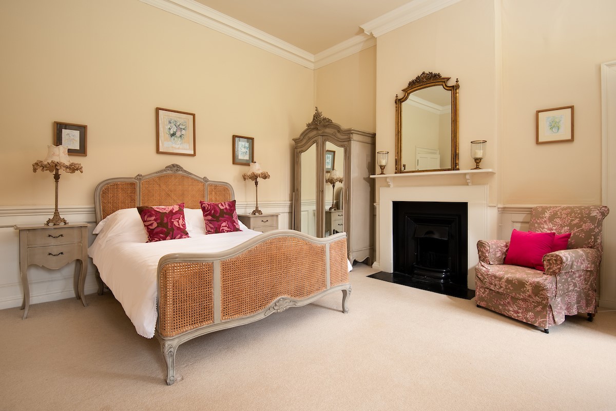 Eslington East Wing - king size bed in bedroom three with occasional chair, decorative fireplace, and large wardrobe