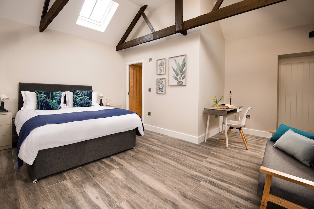 The Steading at West Lyham - bedroom one with king size bed, side tables, desk and sofa