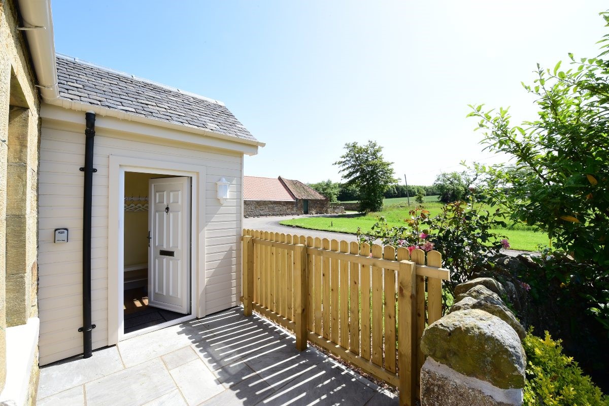 Fordel Cottage - front door of the property with wooden fence to side to keep the garden enclosed