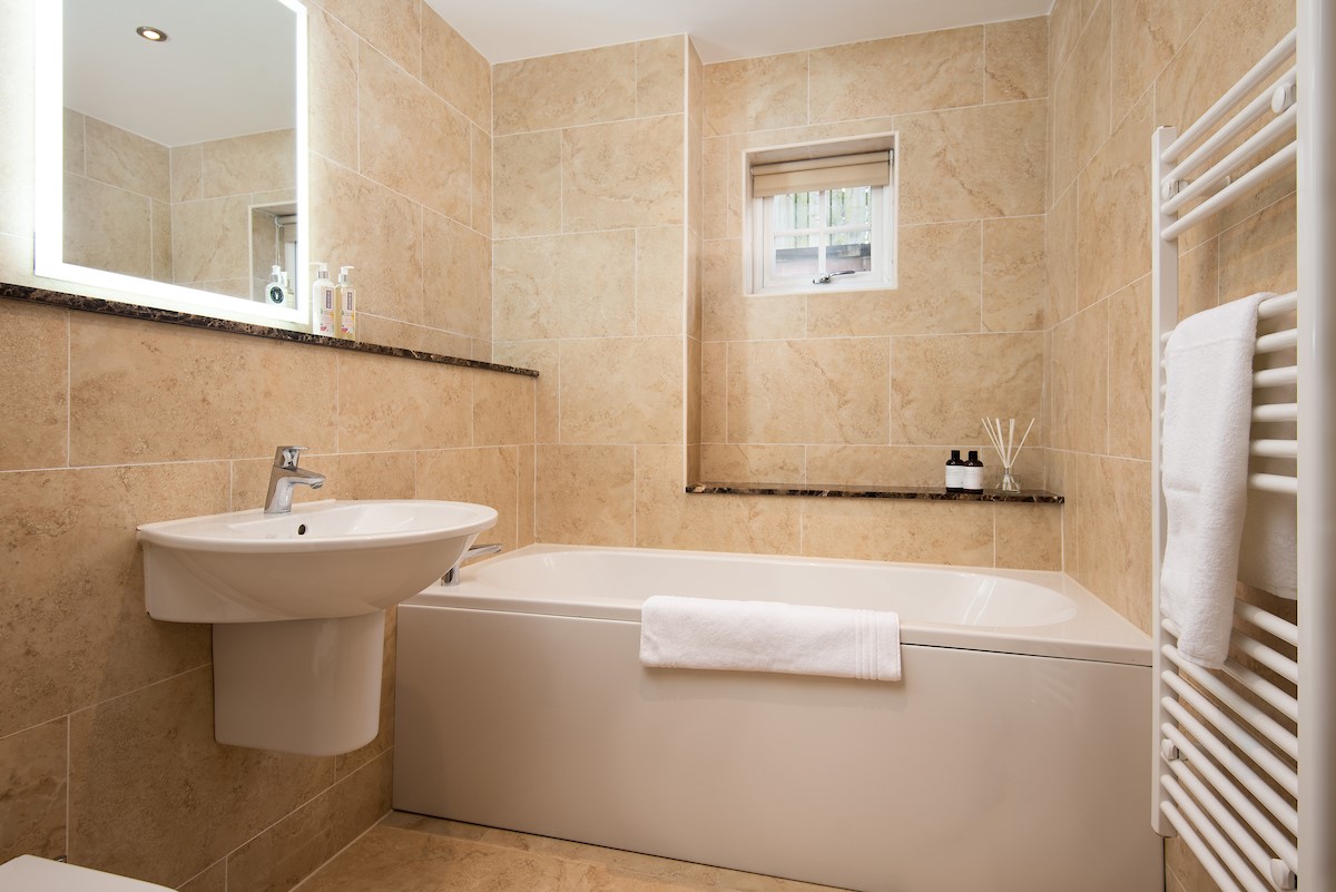 No. 6 - family bathroom with bath, heated towel rail, WC and basin with illuminated mirror above