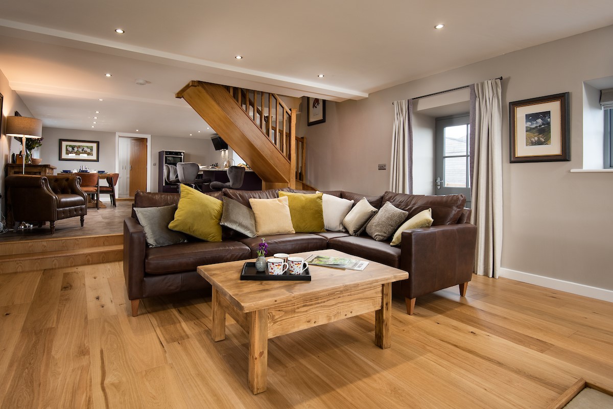 The Granary at Rothley East Shield - living room with 5-seater corner sofa and stairway to first floor