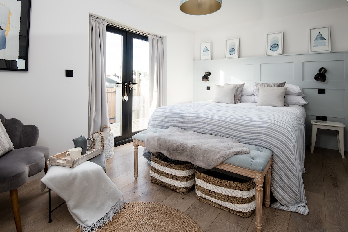 Seaside House - bedroom three with king size bed and stylish panelling, patio doors lead out to the rear garden