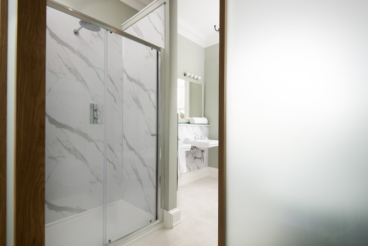 The Linen House - the en suite of bedroom one features a large walk-in shower separated from the rest of the bathroom with a frosted glass screen
