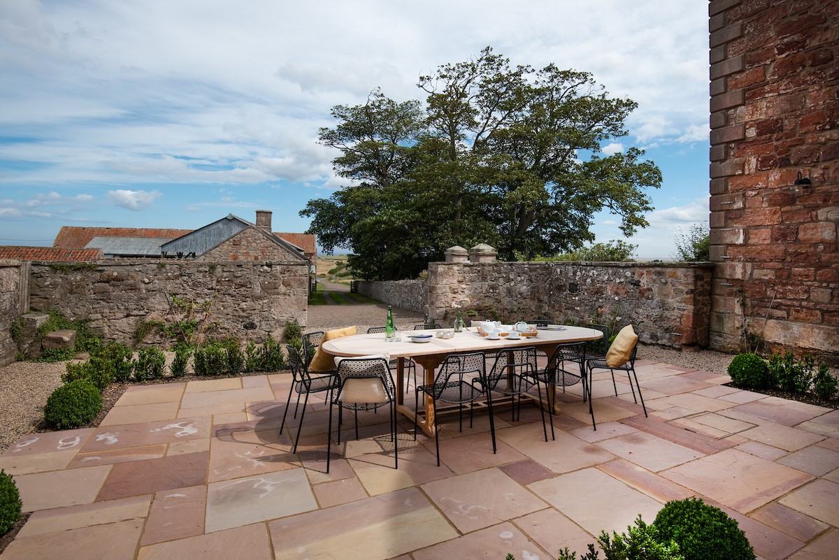 East House - stone courtyard with outside seating for twelve guests leading onto the access lane