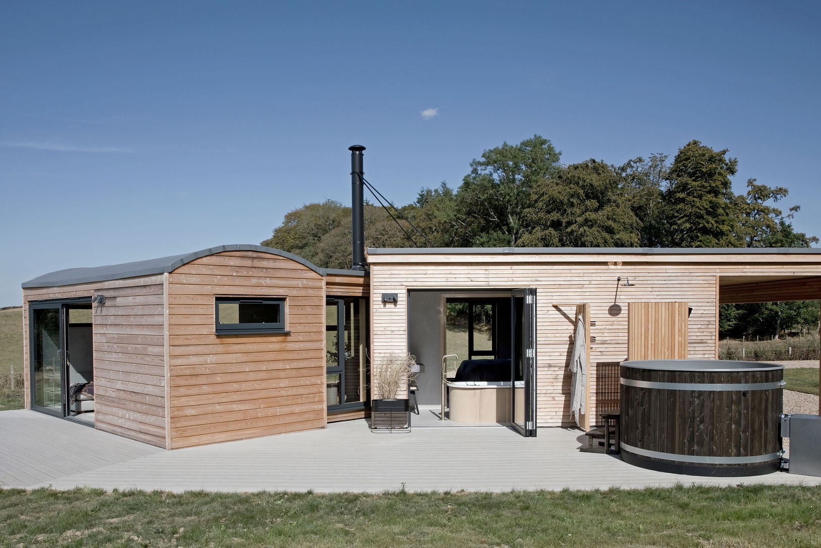 The Railway Carriage - large decking area to the side of the property with hot tub and outdoor shower