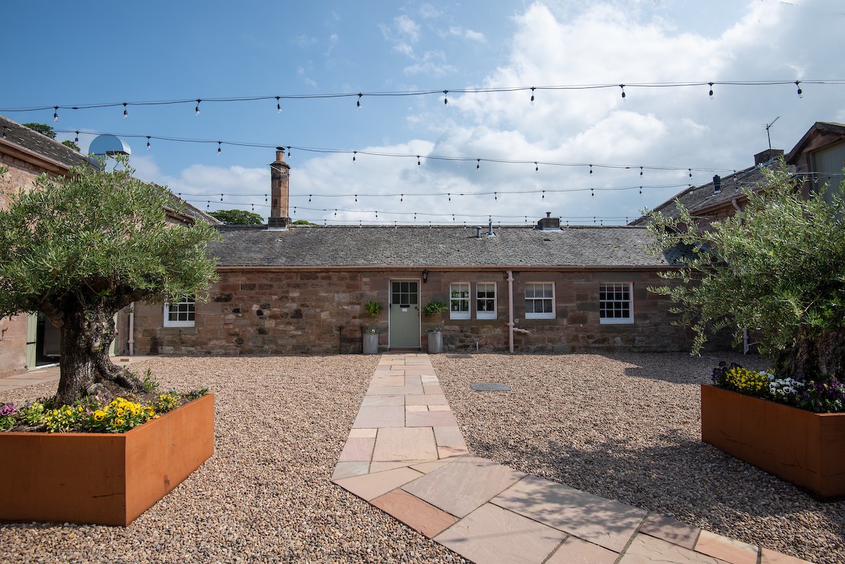Laurel Cottage - front aspect set within a courtyard with atmospheric festoon lighting