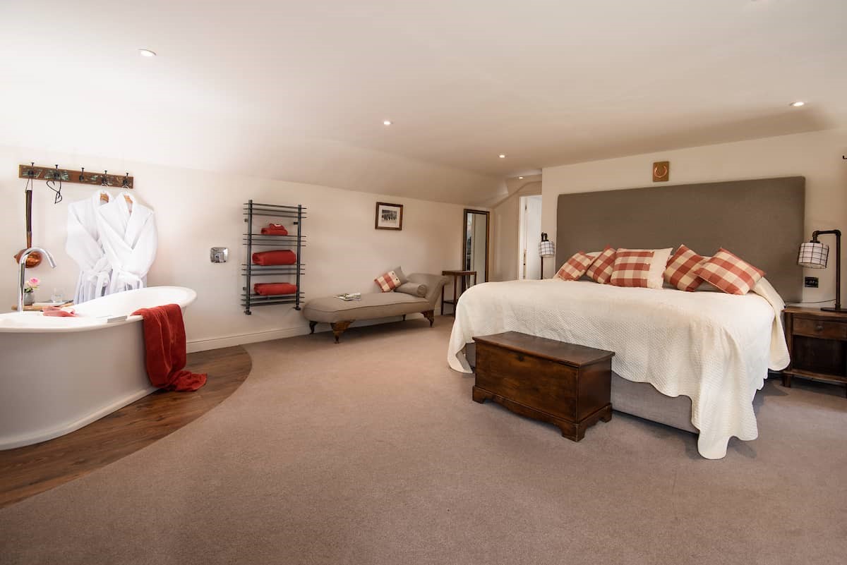 Anvil Cottage - spacious bedroom one with zip and link beds and roll top bath