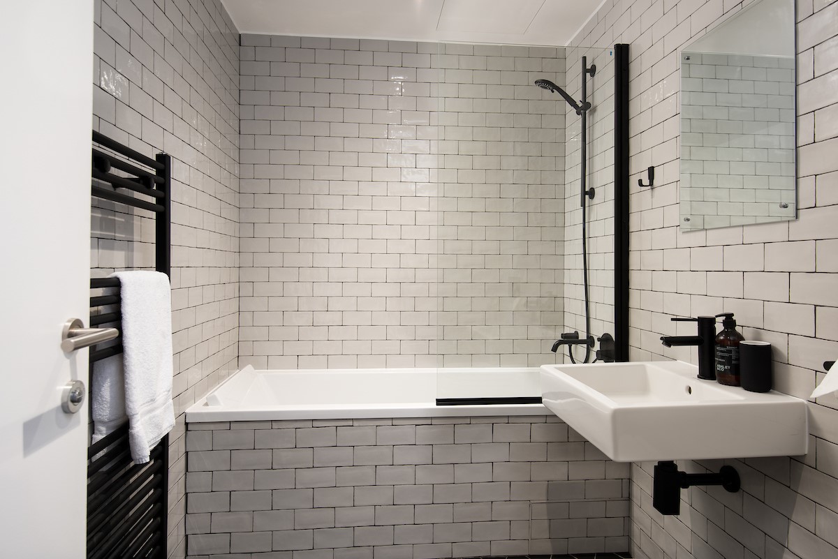 7 The Bay, Coldingham - family bathroom featuring a bath with shower over and stylish monochrome design